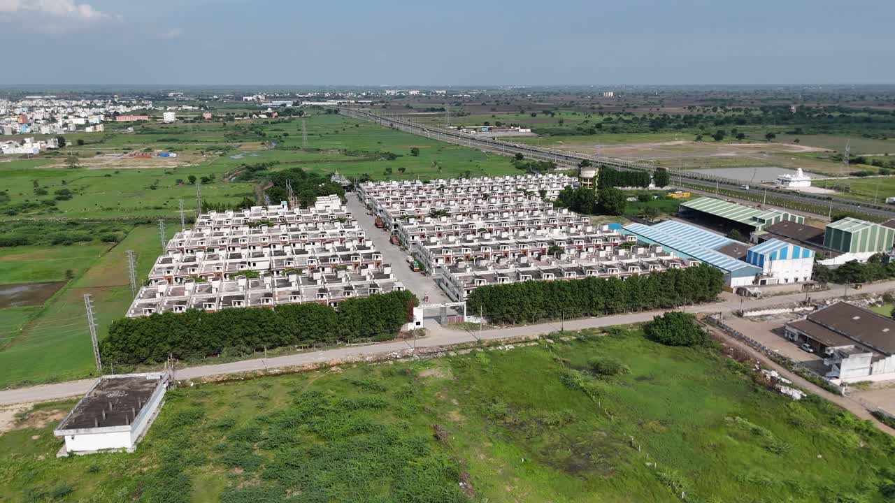 Drone footage of Amaravathi’s rural road system running through green landscapes on a sunny day with houses.