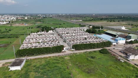 drone footage of amaravathi’s rural road system running through green landscapes on a sunny day with houses.