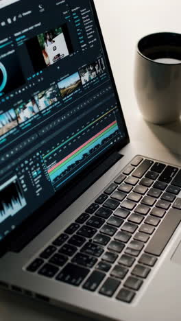 laptop with video editing software and coffee