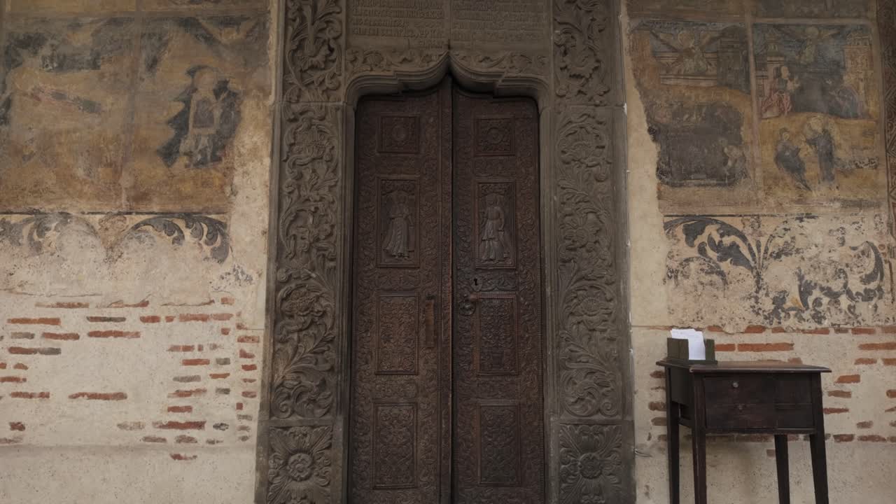 Ornate wooden door and faded frescoes at Stavropoleos Monastery Bucharest