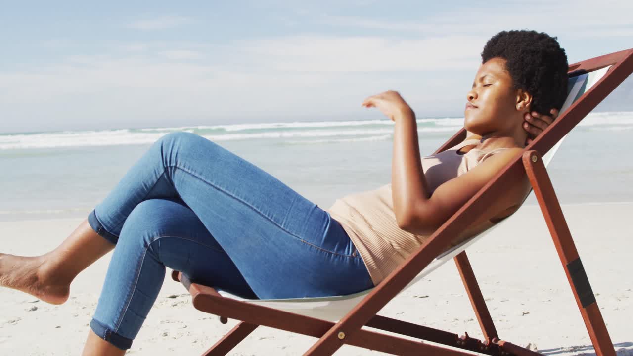 Happy african american woman lying on sunbed on sunny beach