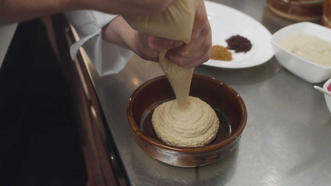 Chef prepares mediterranean hummus starter dish