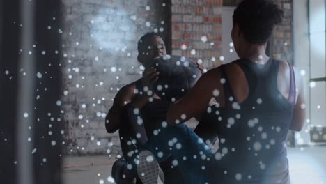 partículas blancas flotando contra afroamericano hombre y mujer trabajando con la pelota de medicina