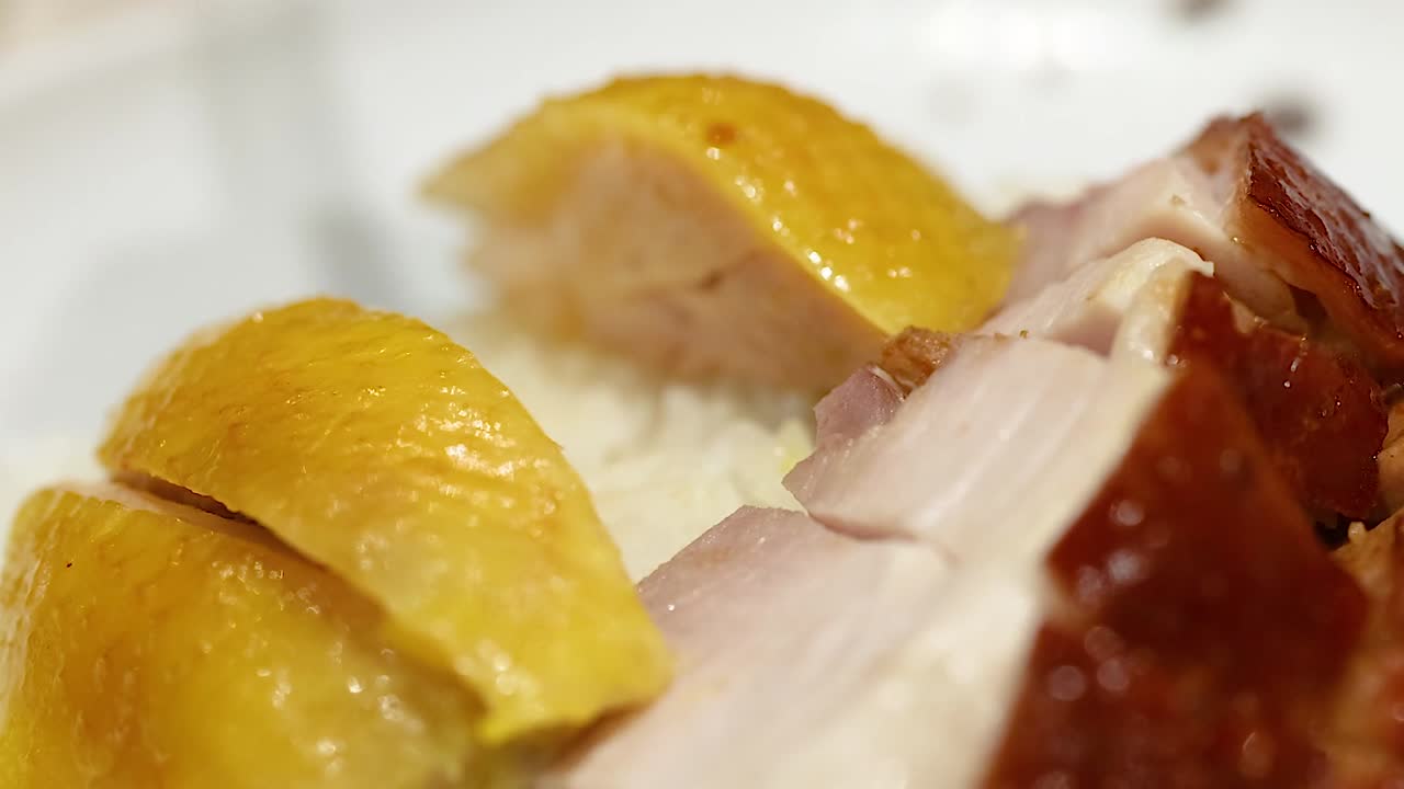 肉の盛り合わせから黄色い皮の鶏肉を箸で持ち上げている極端なクローズアップ