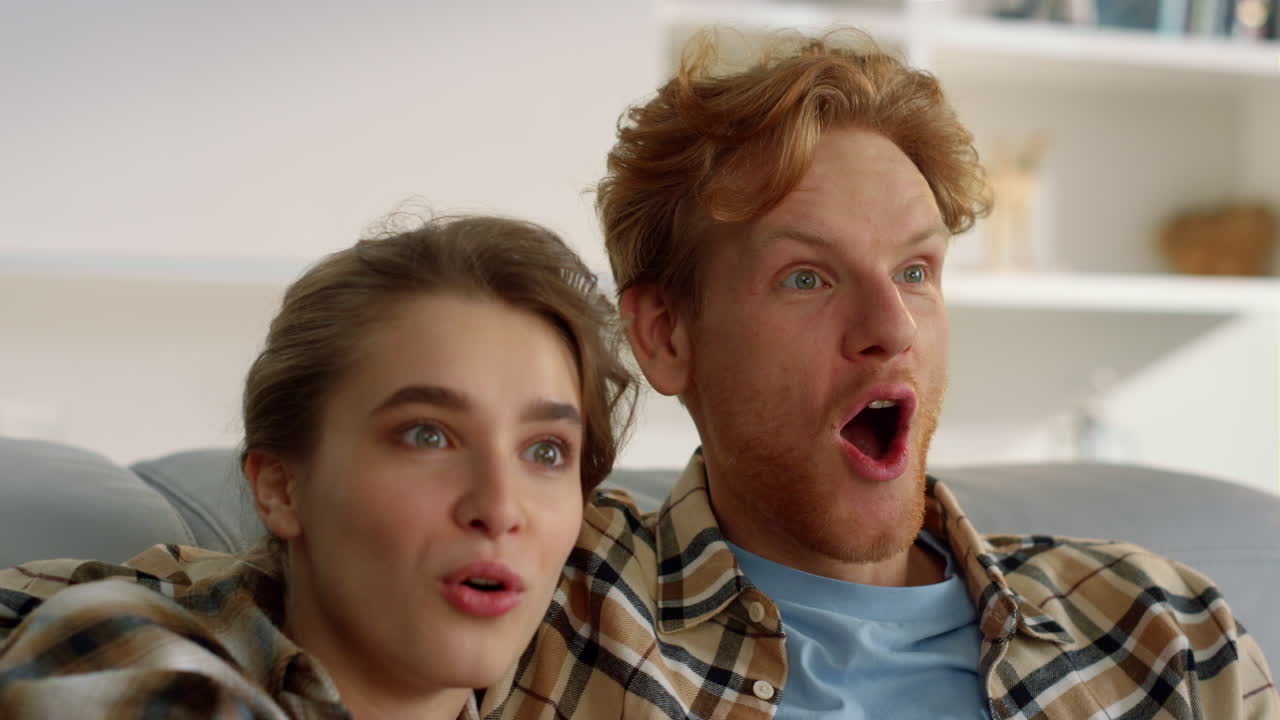 행복 한 커플 이 집 에서 클로즈업 으로 tv 를 보고 있다. 감명 받은 가족 은 스트리밍 영화 를 즐긴다