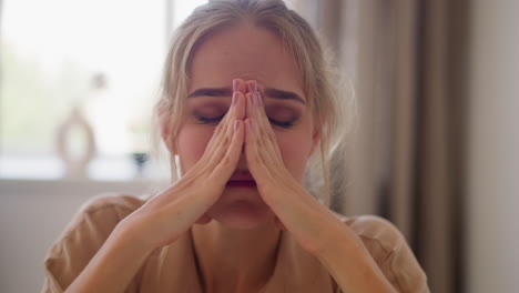 tired woman massages face with hands after work in office