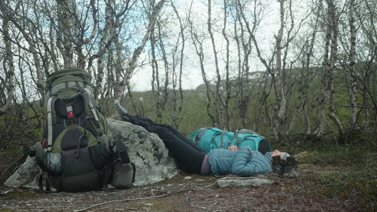 Exhausted Blond Female Hiker Taking a Rest on the Kungsleden in The Swedish Mountains, Backpacking in the Forest, Laying on the Ground