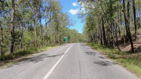 punto de vista de conducción mirando hacia atrás de una carretera rural desierta de queensland con árboles de goma a la sombra: ideal para el reemplazo de la pantalla verde de la escena interior del automóvil