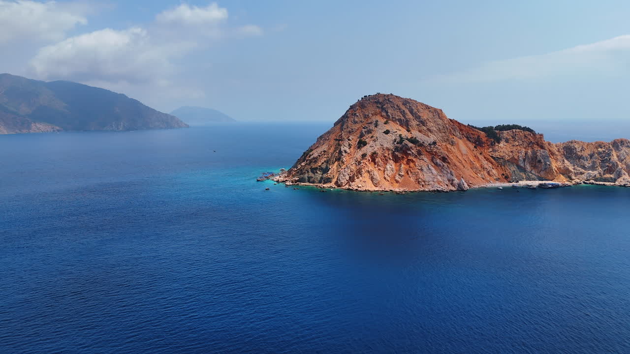 Scenic island amid blue waters. Majestic island with rocky cliffs rises from the calm blue sea under a clear sky, showcasing the beauty of nature