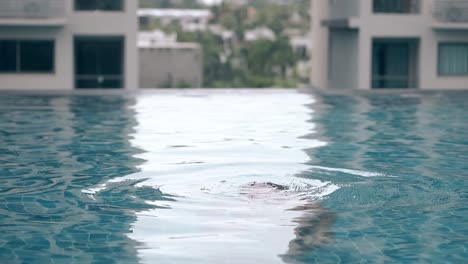 brunette-lady-swims-and-dives-in-pool-on-roof-slow-motion