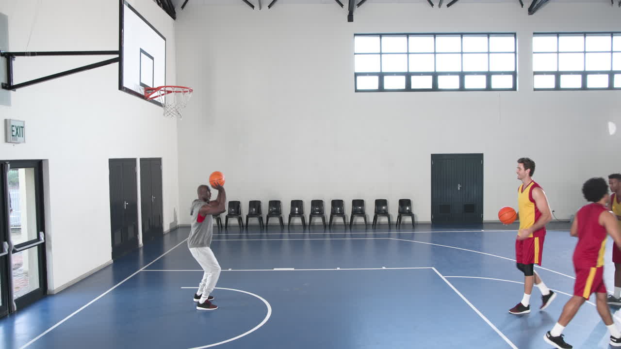 Practicing drills on indoor court, basketball players focusing on teamwork and skills
