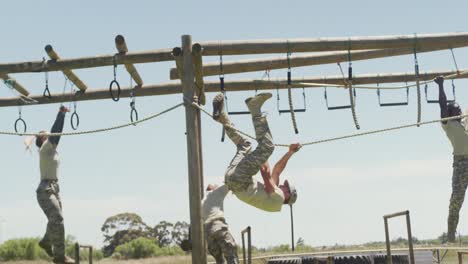 fit diverse group of soldiers using hanging rope and rings on army obstacle course in the sun