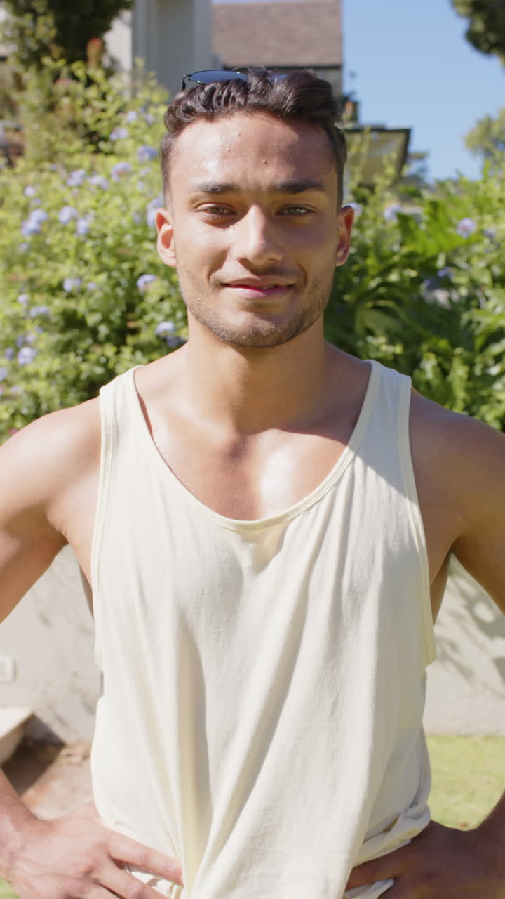 Vertical video of portrait of happy biracial man in garden