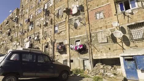 building in a dangerous ghetto with satellite dishes and laundry hanging from the balcony