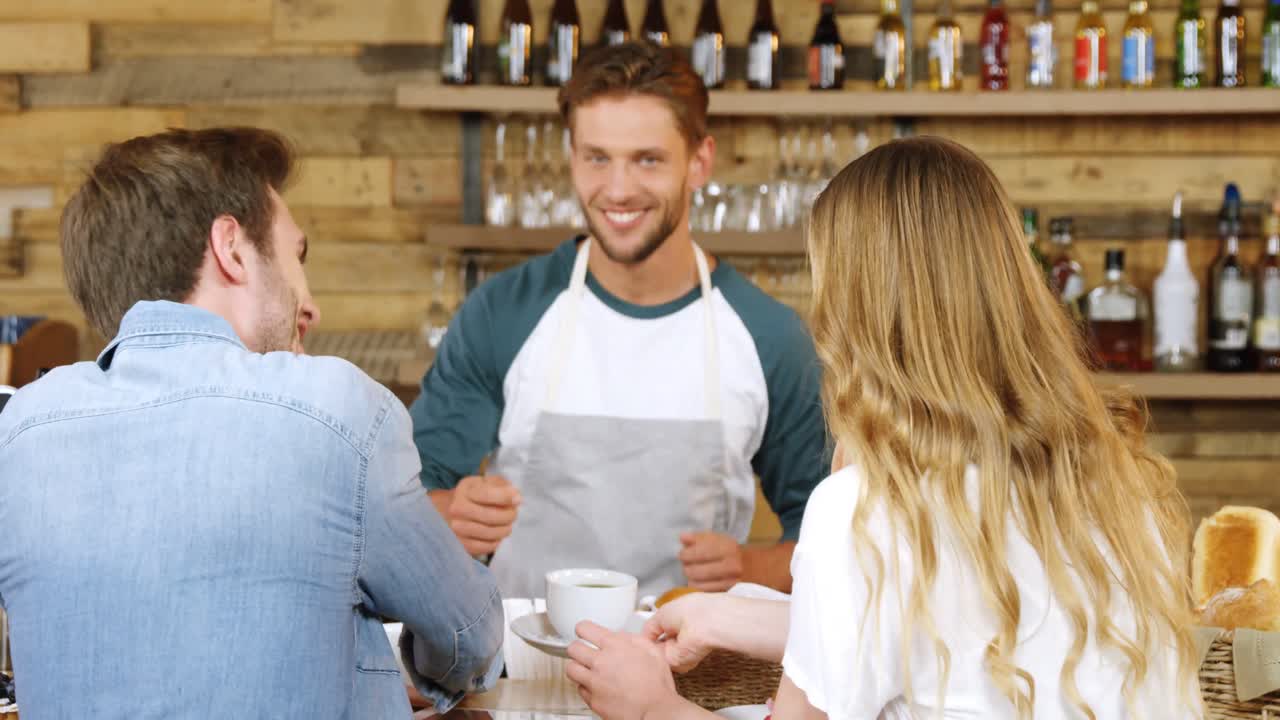 Male waiter serving coffee to couple at counter 4k