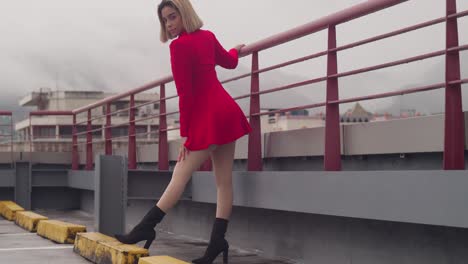 At-a-Port-of-Spain-rooftop,-a-young-Hispanic-girl-in-a-red-dress-stands-against-the-backdrop-of-tall-buildings-in-Trinidad