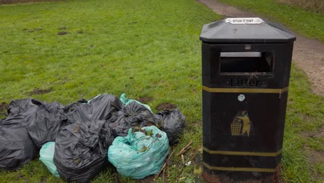 Trash-bin-bags-beside-a-dumpster-at-a-rural-area-in-Thetford,-England---panning-shot