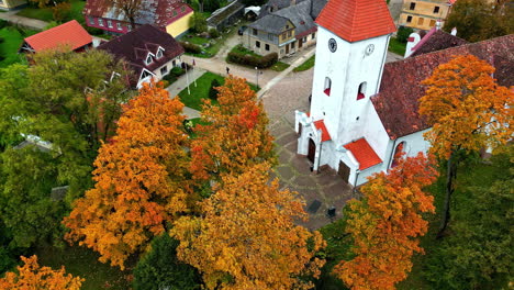 tower of talsi evangelical lutheran church with autumn trees in talsi, latvia. orbiting drone shot