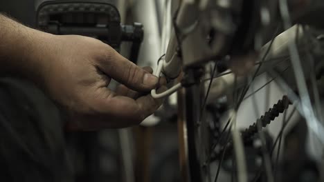 a bicycle mechanic installing a brake cable housing on a bicycle frame