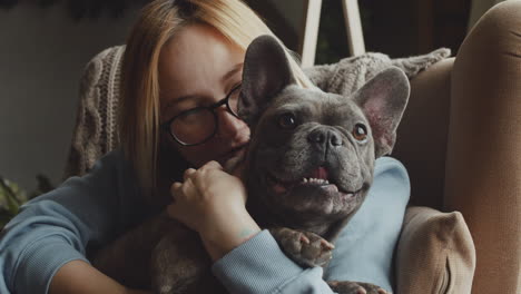 Nahaufnahme-Einer-Rothaarigen-Frau,-Die-Ihren-Bulldoggenhund-Streichelt,-Während-Sie-Zu-Hause-Auf-Dem-Sofa-Im-Wohnzimmer-Sitzen-2