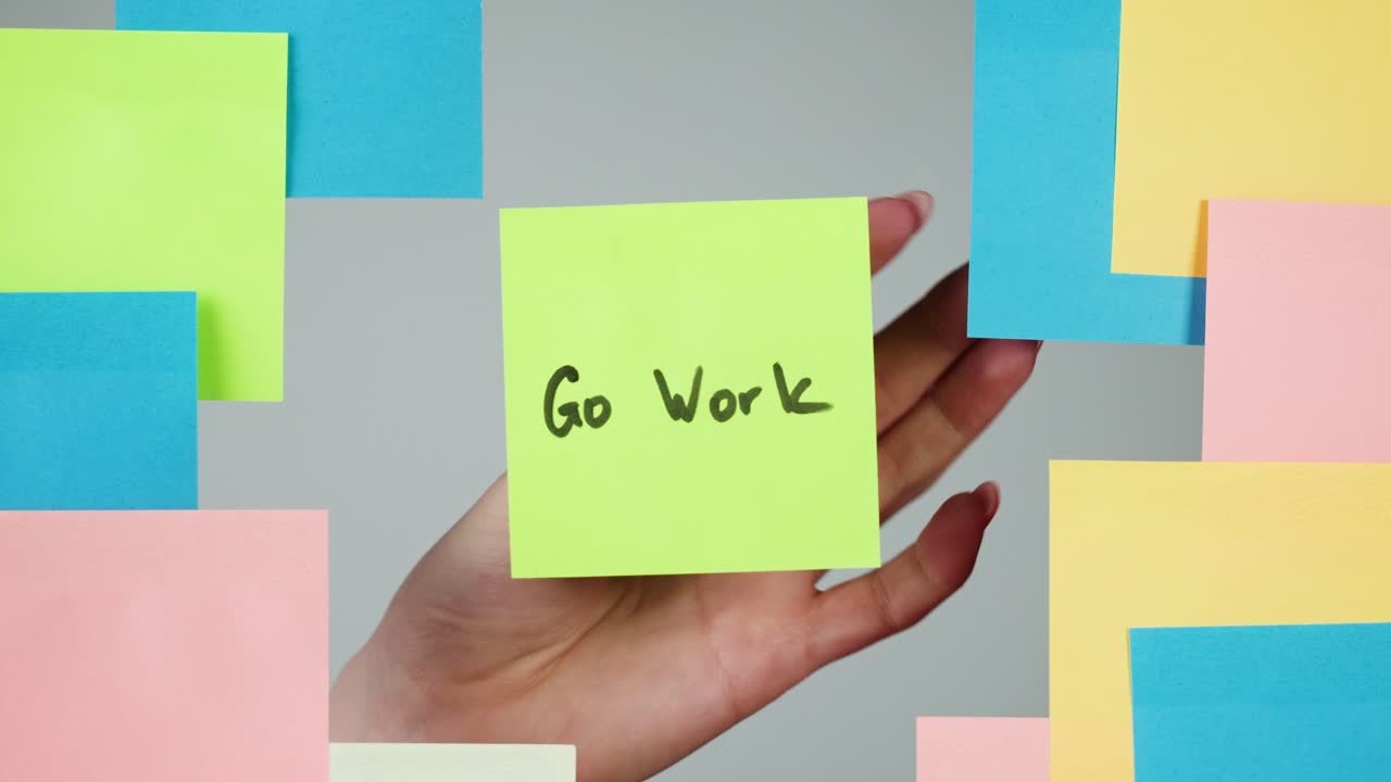 Hand Placing Motivational 'Go Work' Sticky Note on Wall