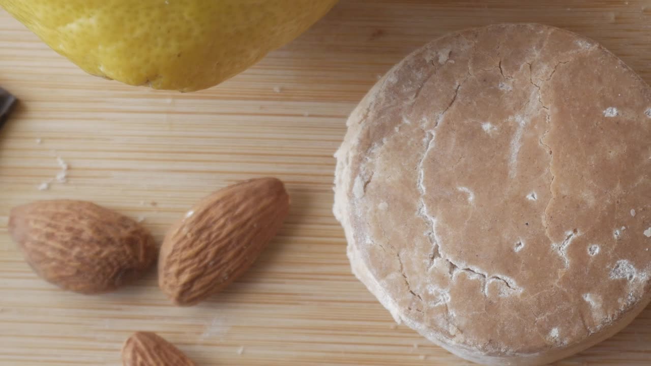 Traditional Spanish Christmas sweet polvoron with almonds, dark chocolate, lemon, and a rustic wooden background.