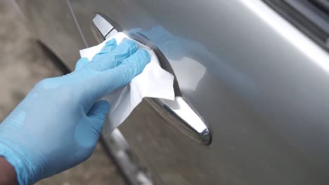 cleaning a car door handle with gloves and tissues