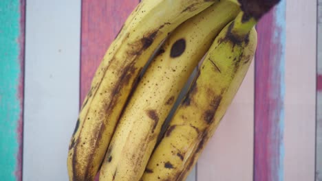 bunch of slightly ripe bananas on a wooden surface