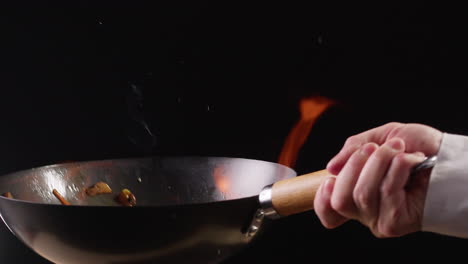 stir-frying vegetables and shrimp in a wok with flames