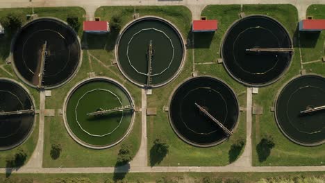 aerial overhead shot of sewage treatment plant-waste water treatment facility. almost static shot. just some birds are flying over the water tanks.