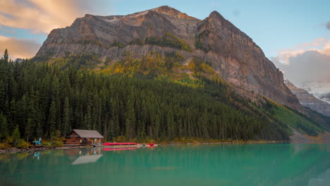 time lapse of lake louise, canada, clouds above water, hill, forest and lodge in banff national park