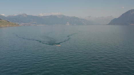 Beautiful-aerial-of-small-motorboat-driving-over-lake-Geneva