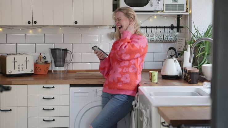 Donna che usa il telefono in cucina