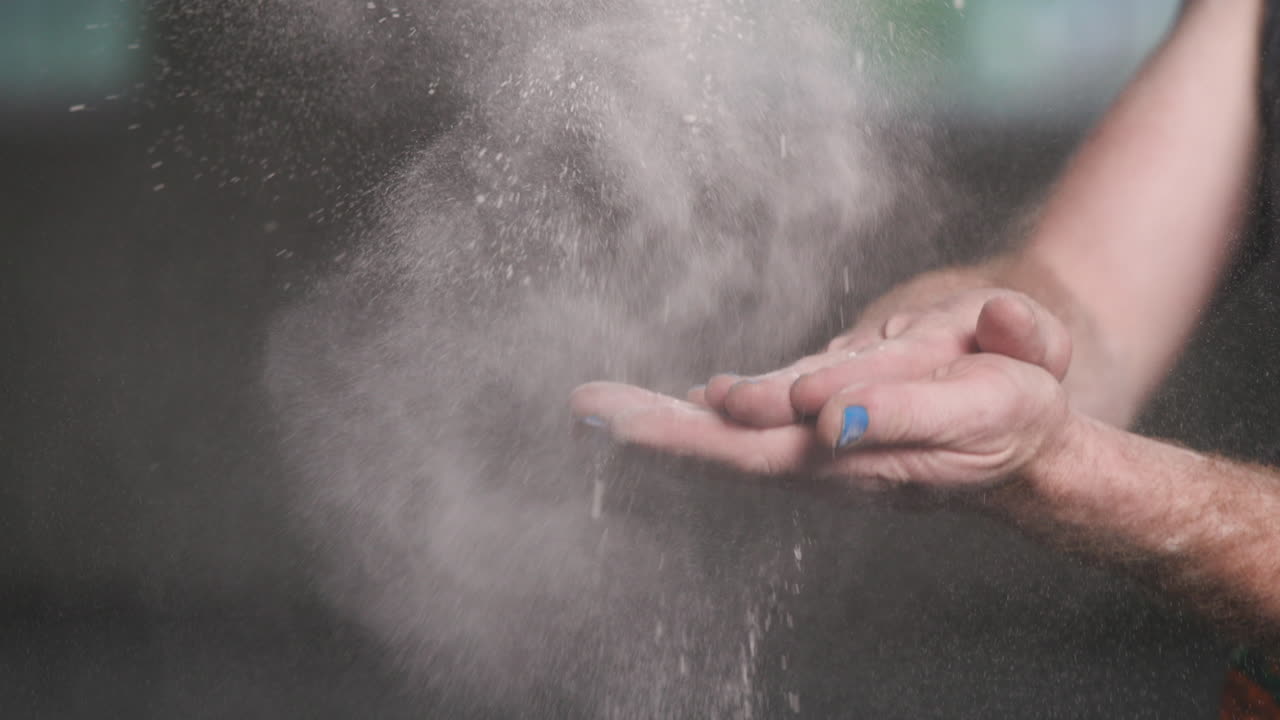 Close video footage of hands holding flour and clapping together to create a powder cloud.