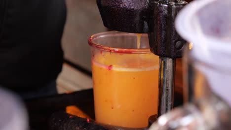 fresh orange juice being made with a hand-crank juicer