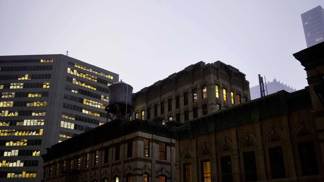 Quando scende il crepuscolo, gli edifici della città si animano con le finestre illuminate.