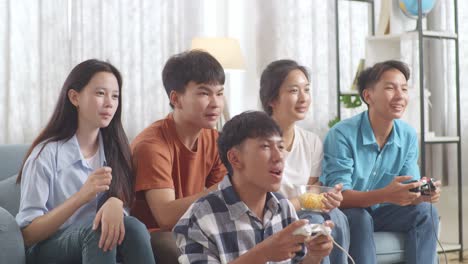 asian teenagers playing video games and celebrating victory at home