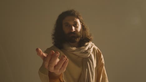 hombre con túnicas de pelo largo y barba que representa la figura de jesucristo ofreciendo una mano de ayuda