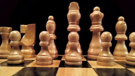 truck shot from left to right of white chess pieces standing on a chessboard on a black background