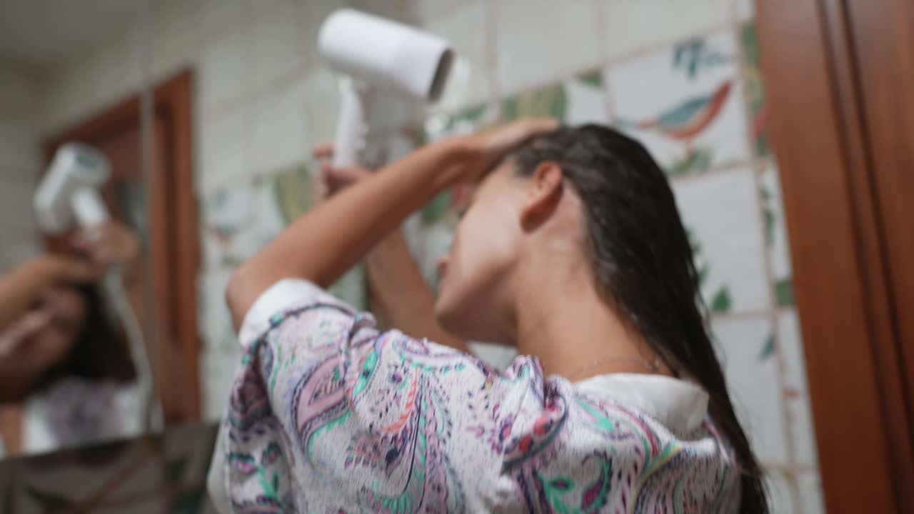 욕실에서 머리를 건조시키는 여자