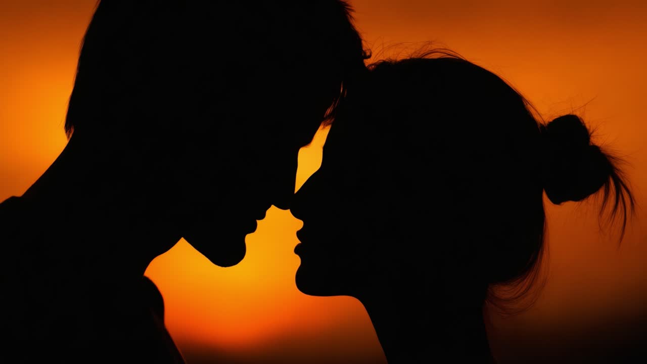 A tender moment captured in silhouette against a vibrant sunset, showcasing the intimacy and connection between two individuals leaning in for a kiss