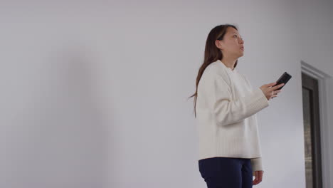 stressed or anxious woman sitting on floor leaning against wall at home reacting to internet or social media news message or story on mobile phone 6