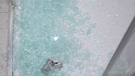 shattered glass on the floor from a broken shower enclosure