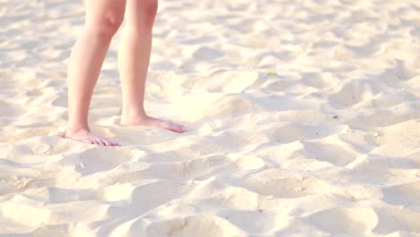 person walking barefoot kicking sand on karon beach, phuket, thailand