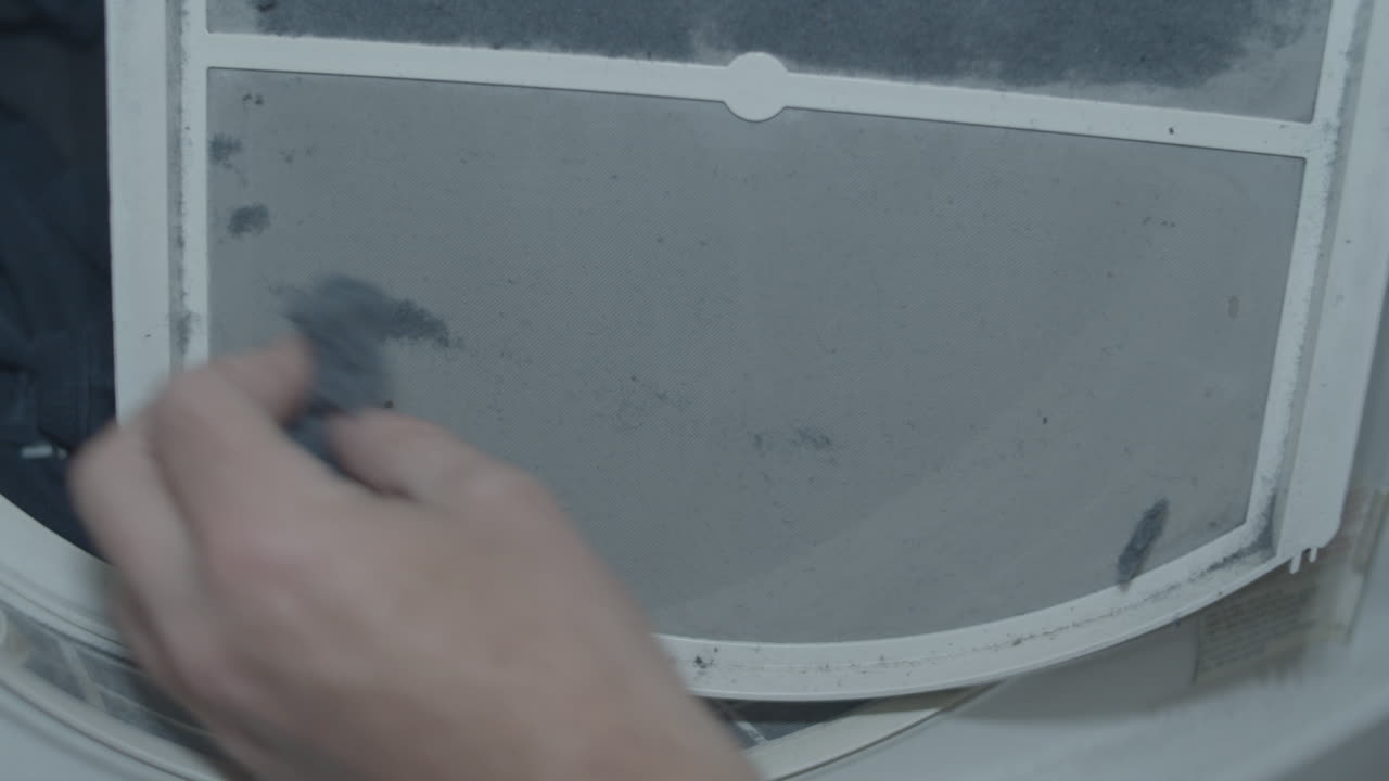 eliminación manual de pelusas de la trampa de pelusas frente a la secadora de ropa llena