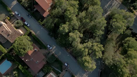 aerial establishing shot above european countryside neighborhood gardens pools for swimming and cars driving by