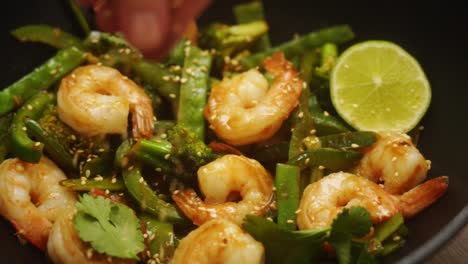 unrecognizable person serving appetizing dish with shrimps with sesame seeds