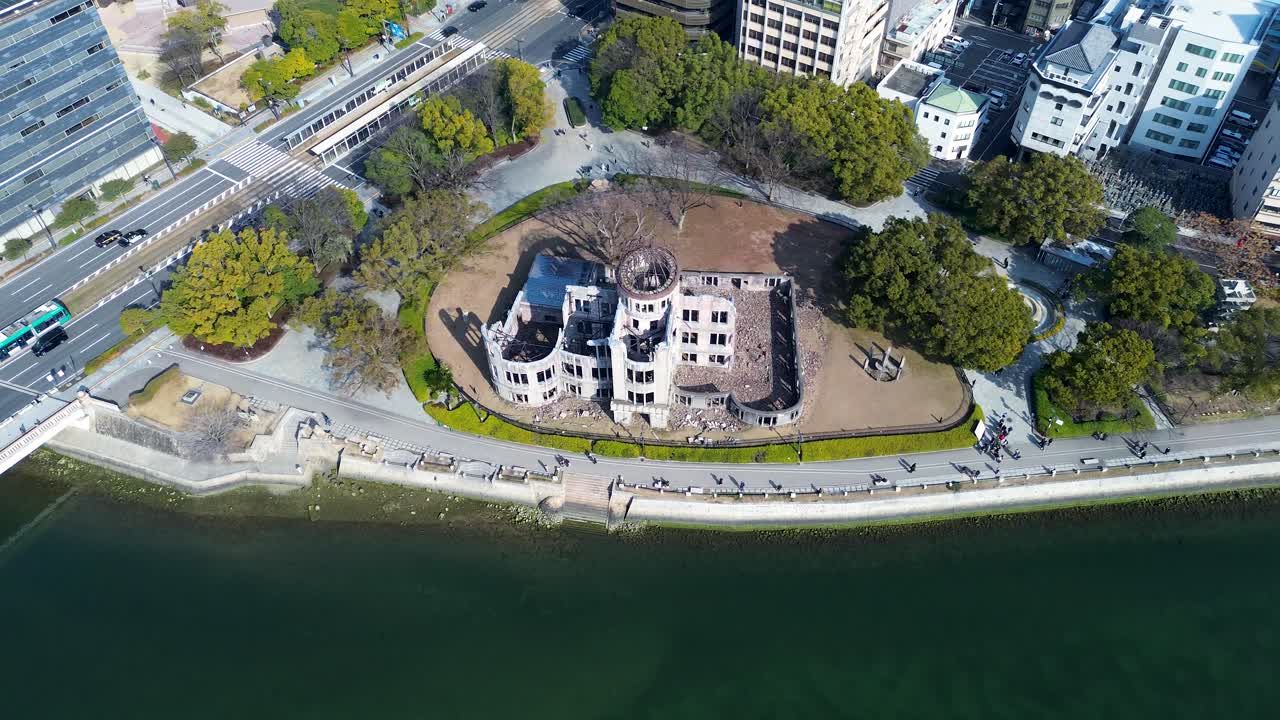 Dronen ilmakuva historiallisesta Genbaku Dome -maamerkistä Motoyasu-joen rannalla, taustalla lauttavene ja kaupunkirakennuksia. Hiroshiman rauhanpuiston muistomerkki, Japanin matkailu.
