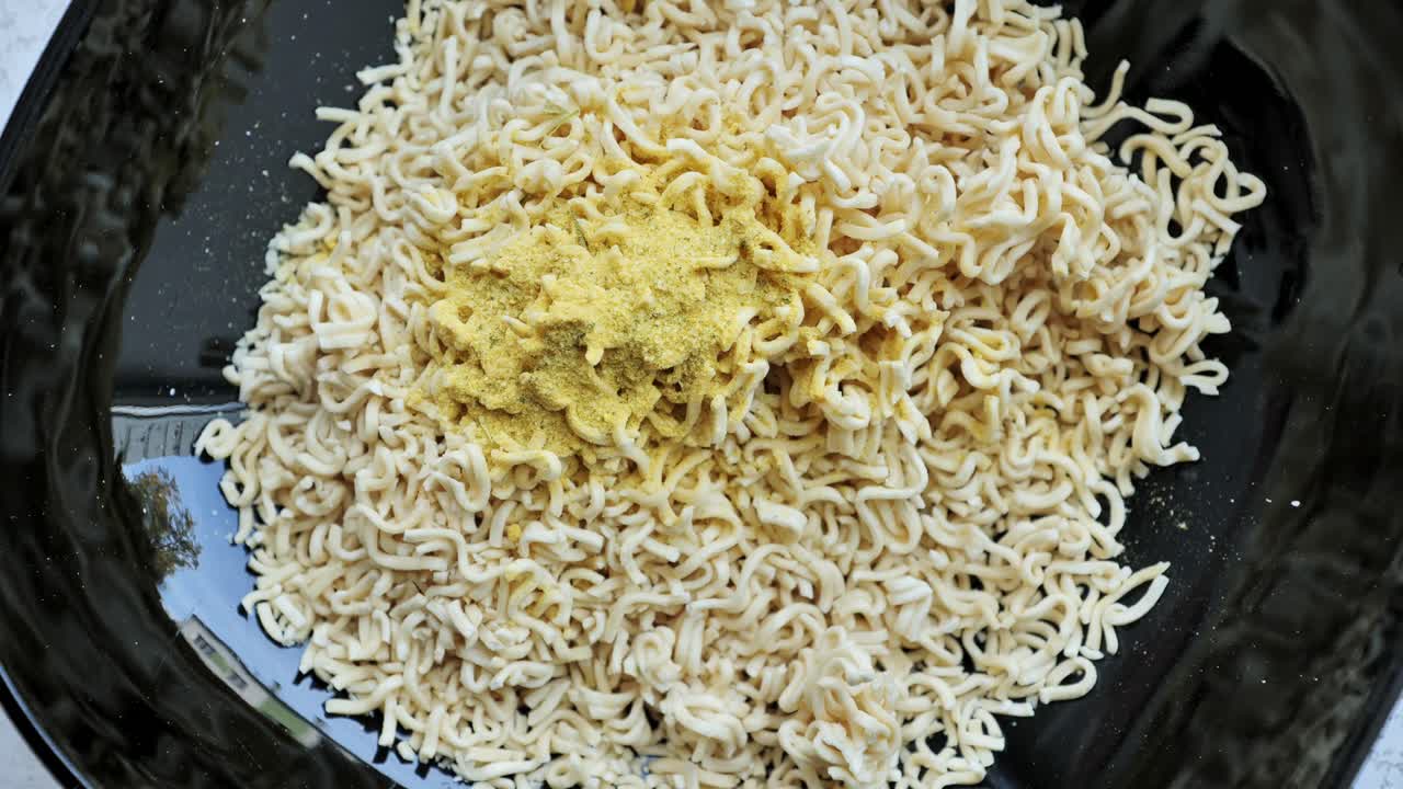 Spice blend sprinkled over dry noodles as part of quick instant ramen prep step