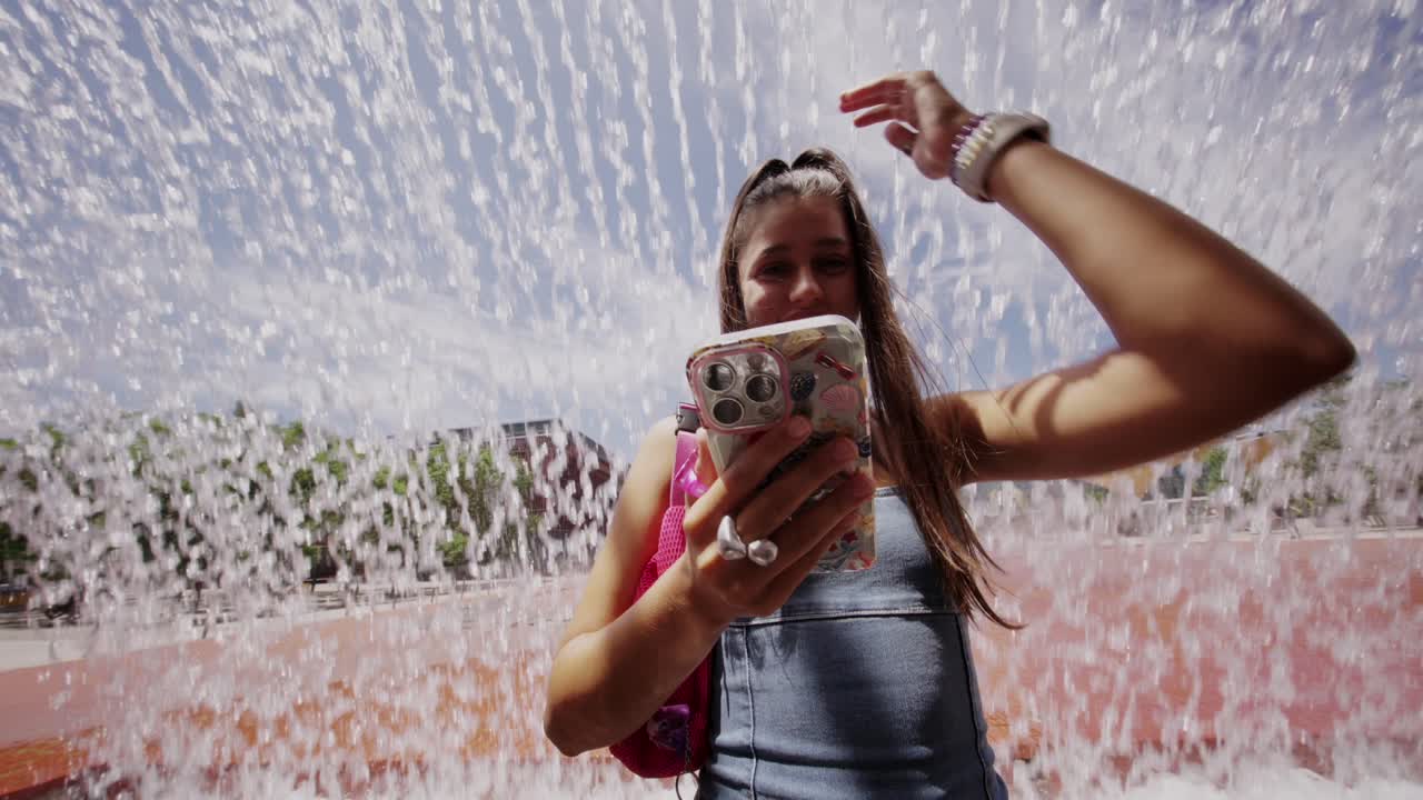 Jovem Mulher Usando Smartphone ao Lado de uma Fonte.